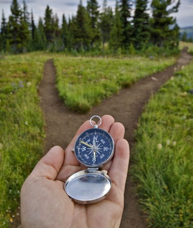 Man holding a compass trying to find the right path