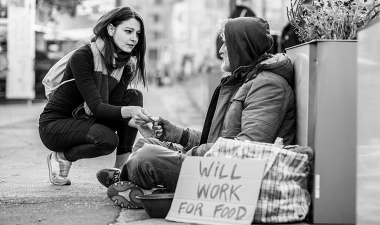 A woman showing "cura personalis" to a homeless man by caring for the whole person