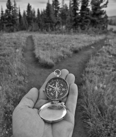 Man holding a compass trying to find the right path